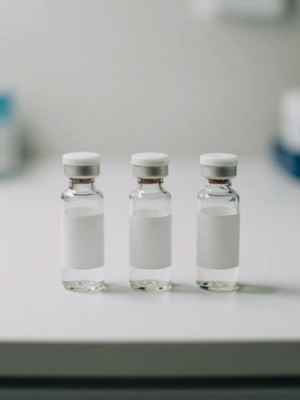 Three unlabeled clear vials arranged in a row on a white lab surface.