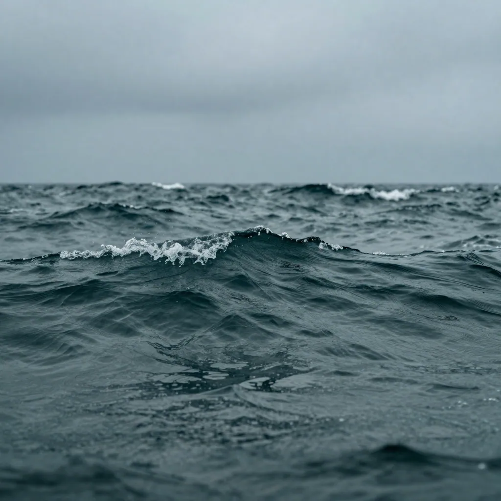 Close-up of choppy dark teal sea water with whitecaps under a heavy grey sky.