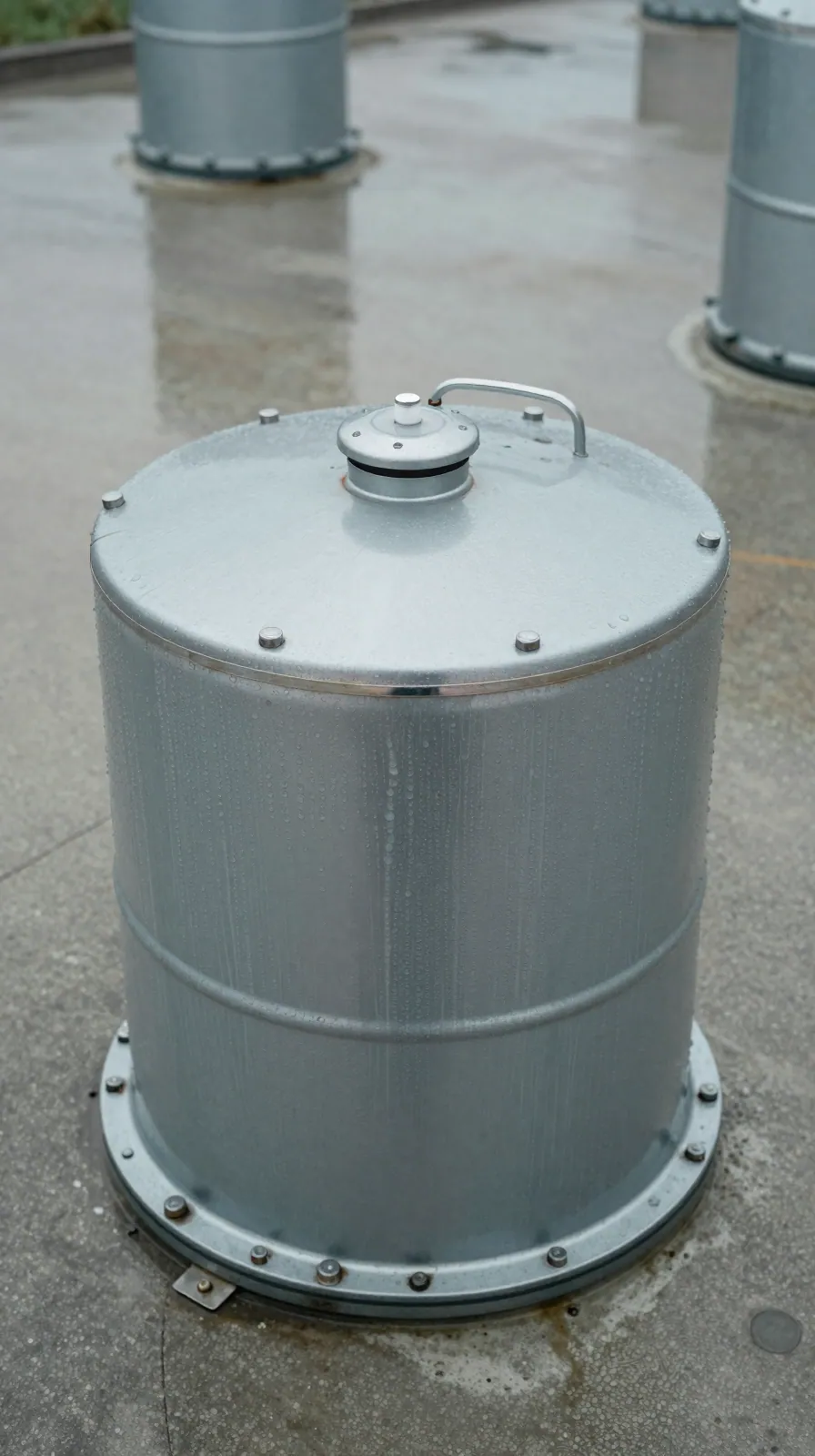 Condensation droplets on the metal rim of a fuel tank fill point in damp concrete.